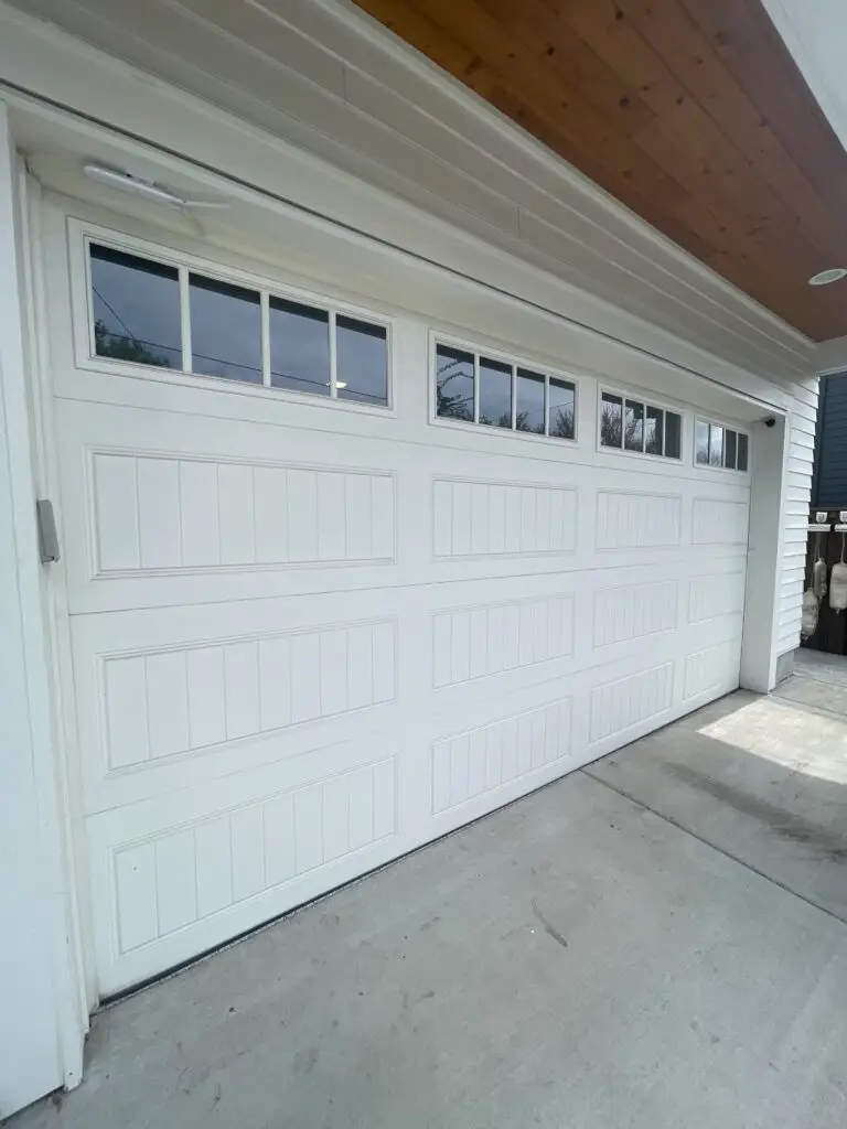 Long panel garage door, white in color with windows, panel replacement.